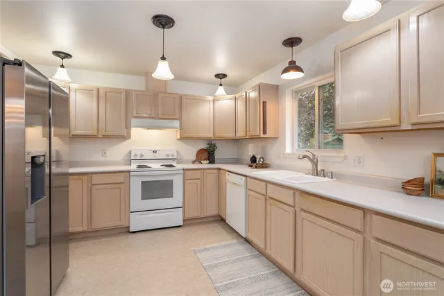 a kitchen with a white center island a sink stainless steel appliances and cabinets