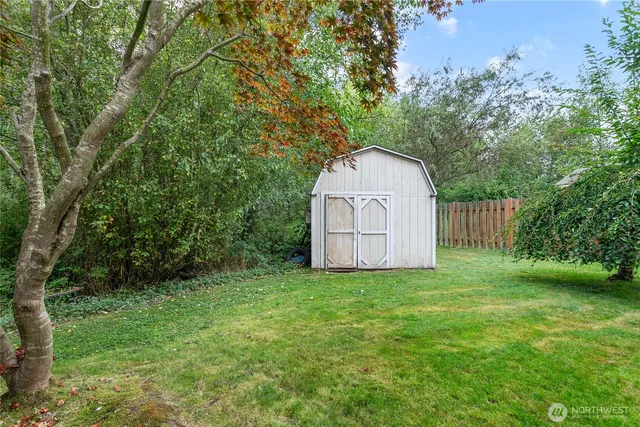 a view of a tiny house with a yard and large trees