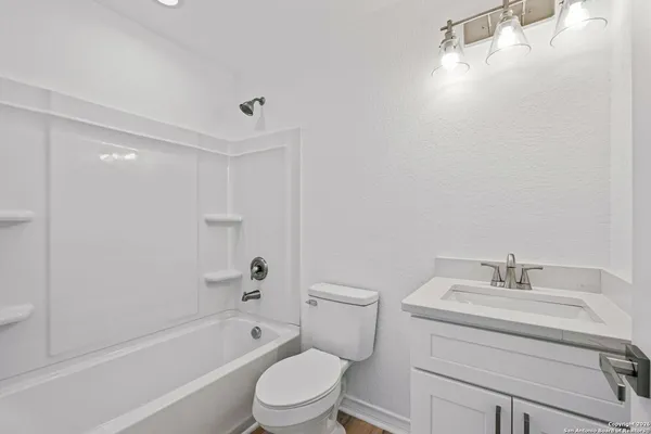 a bathroom with a bathtub shower sink vanity and toilet