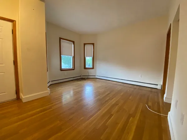 a view of an empty room with wooden floor and a window