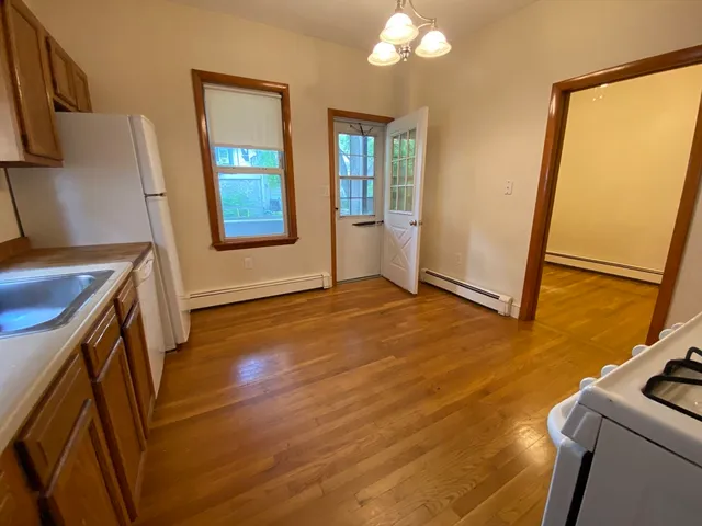a view of a kitchen with fridge and wooden floor