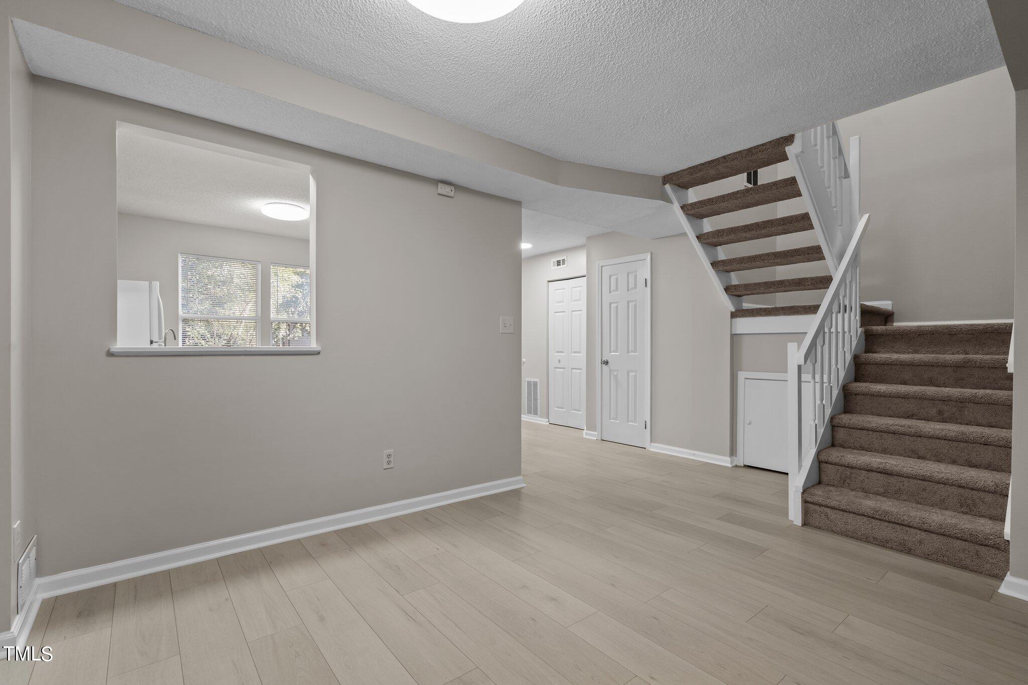 7837 Stephanie Lane Raleigh, NC 27615 - Photo 12 of 27 a view of an empty room with wooden floor and stairs