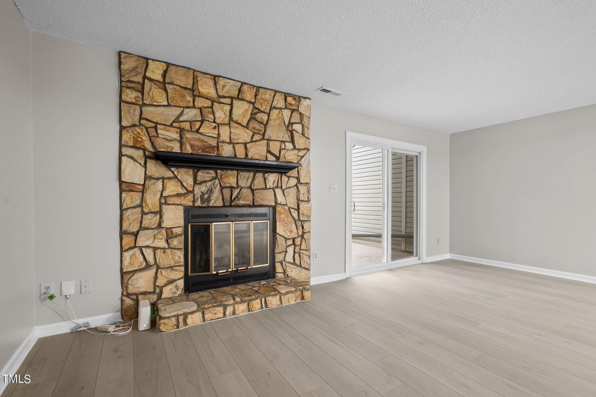 7837 Stephanie Lane Raleigh, NC 27615 - Photo 9 of 27 a view of an empty room with wooden floor fireplace and a window