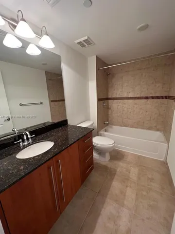 a bathroom with a granite countertop sink a toilet a mirror and bathtub