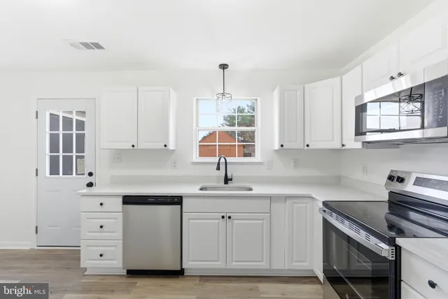a kitchen with white cabinets stainless steel appliances and a window
