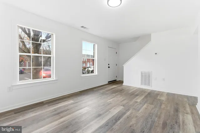 an empty room with wooden floor and windows