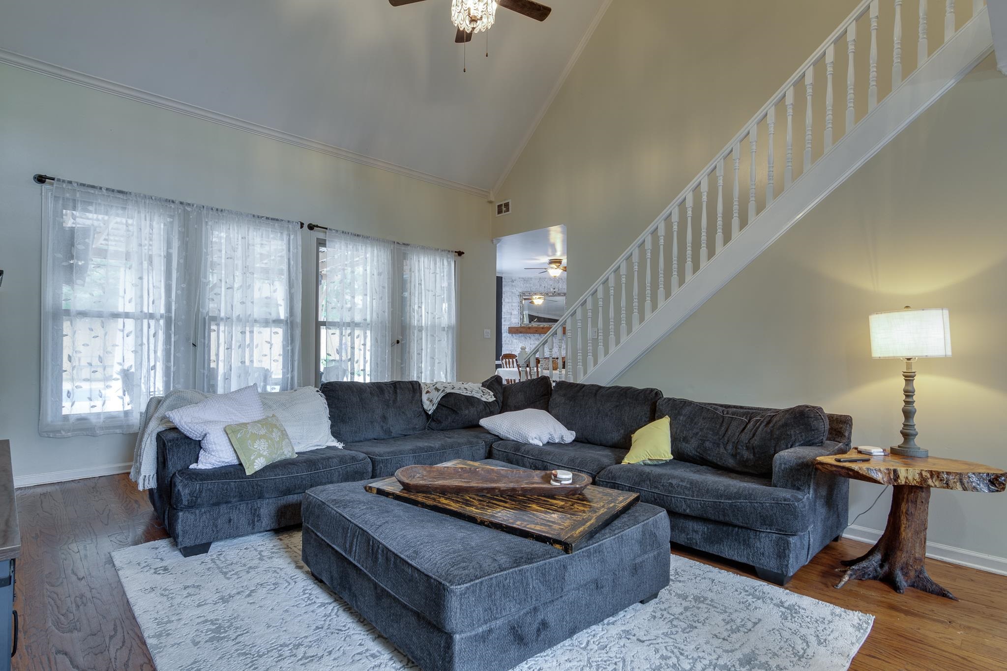 779 Early Earner Cove Collierville, TN 38017 - Photo 6 of 29 Living room featuring vaulted ceilings, wood-finish flooring, a white staircase with balusters, and a decorative ceiling fan