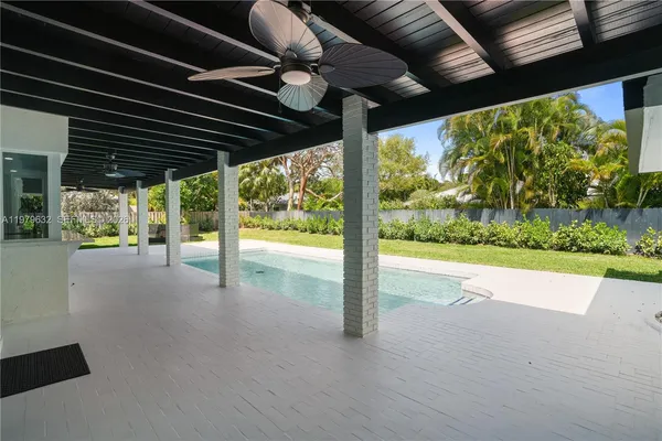 an aerial view of a house with swimming pool and large trees