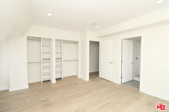 a view of an empty room with wooden floor and closet