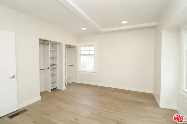 a view of an empty room with wooden floor and closet