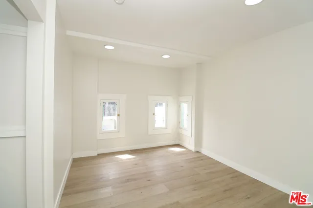 a view of empty room with wooden floor and fan