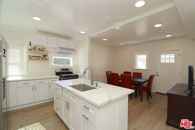 a kitchen with a stove a sink a kitchen island with chairs and wooden floor