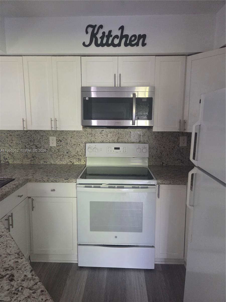 8365 Southwest 152nd Avenue, Unit 3 Miami, FL 33193 - Photo 13 of 25 a kitchen with stainless steel appliances granite countertop a stove a microwave and a refrigerator