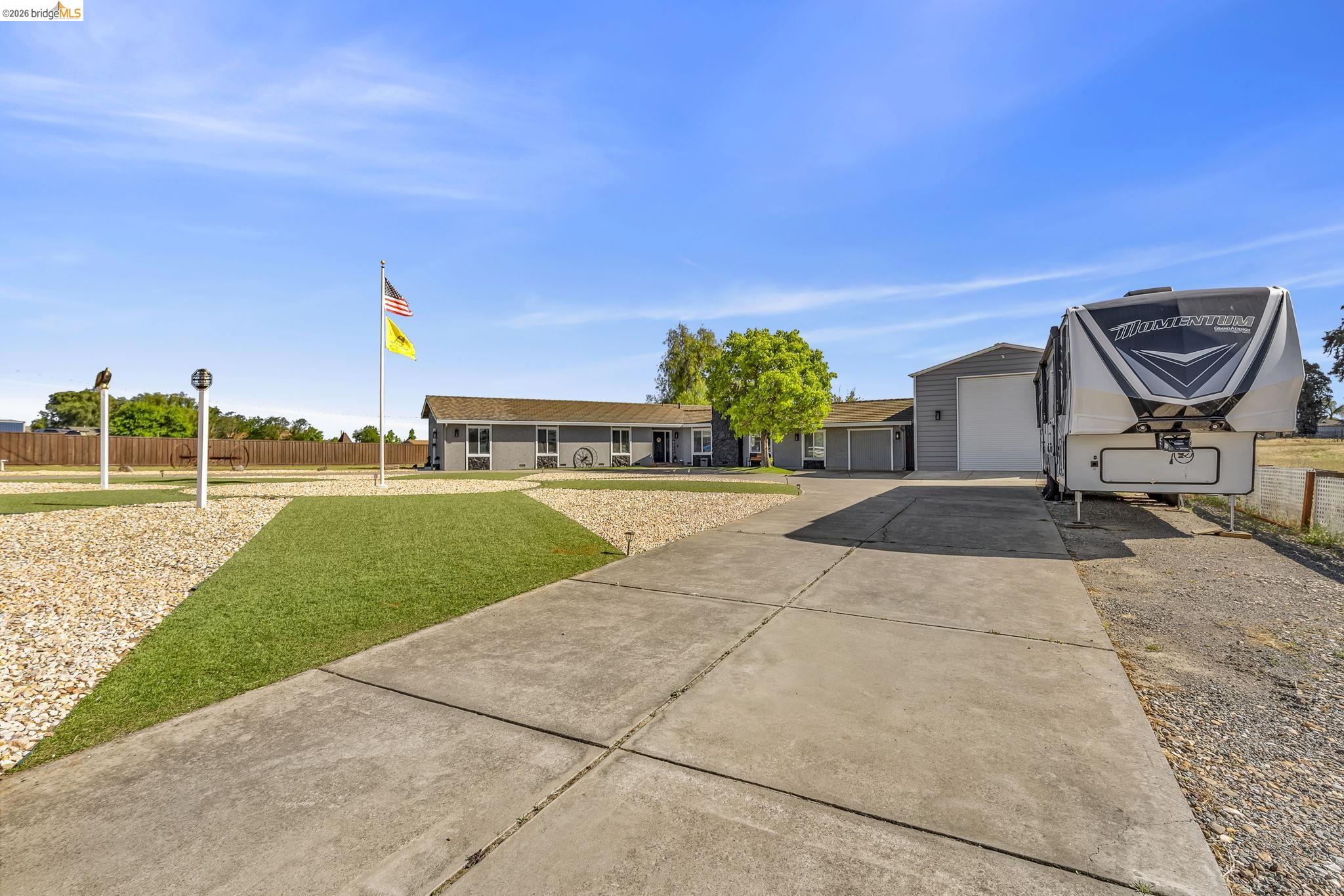 59 Old Stagecoach Road Brentwood, CA 94513 - Photo 11 of 70 Spacious concrete driveway with a gravel border leading to a detached garage and a gray-sided residence