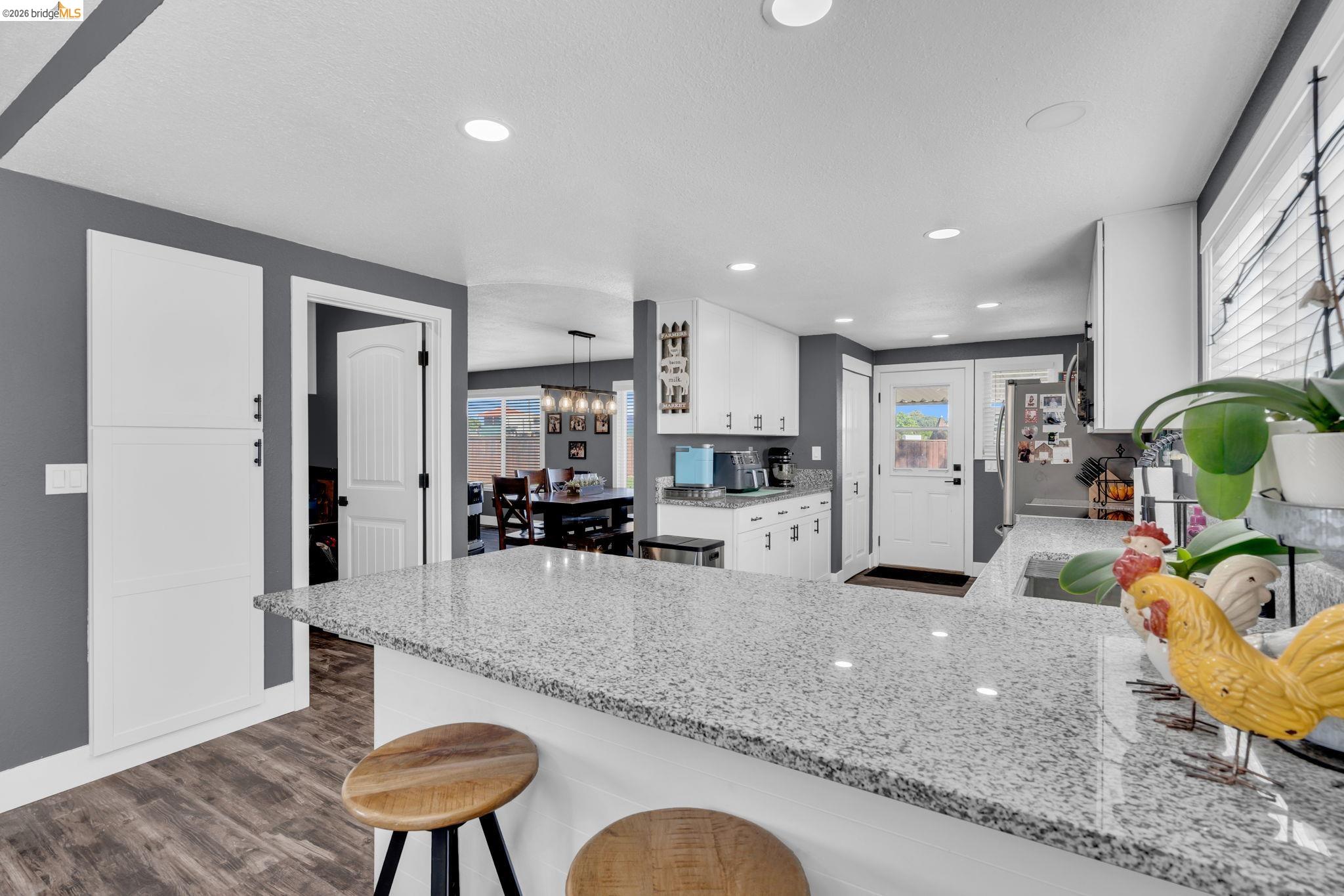 59 Old Stagecoach Road Brentwood, CA 94513 - Photo 20 of 70 Kitchen featuring a spacious island with a speckled countertop, white cabinetry, recessed lighting, and wood-finish flooring