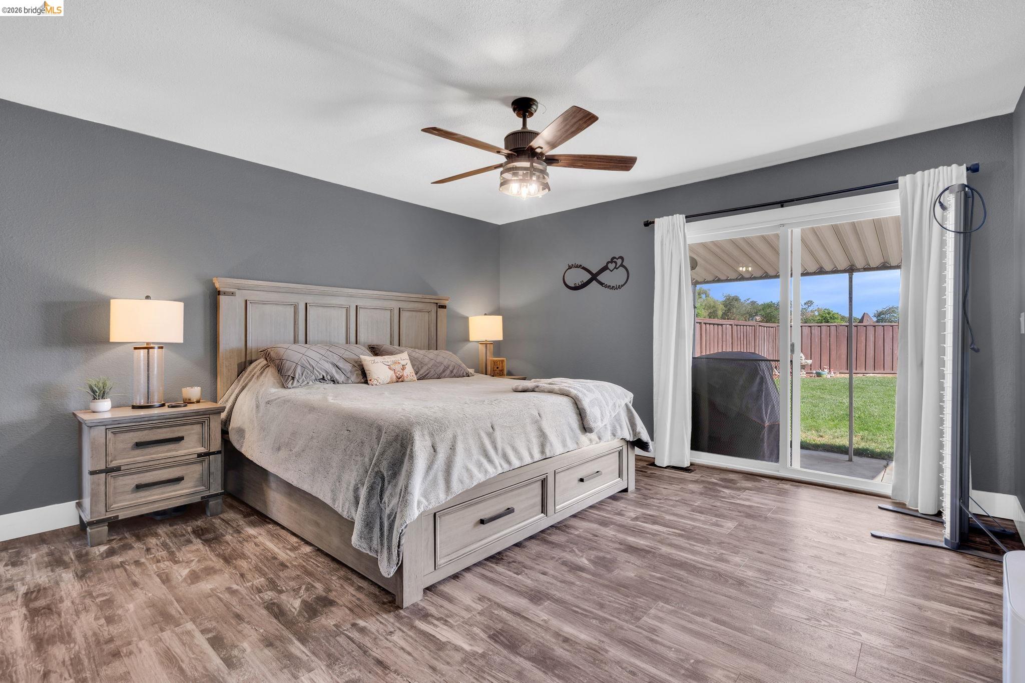 59 Old Stagecoach Road Brentwood, CA 94513 - Photo 25 of 70 Spacious room featuring wood-finish flooring, a ceiling fan with integrated lighting, and a sliding glass door providing direct access to the exterior patio and fenced yard