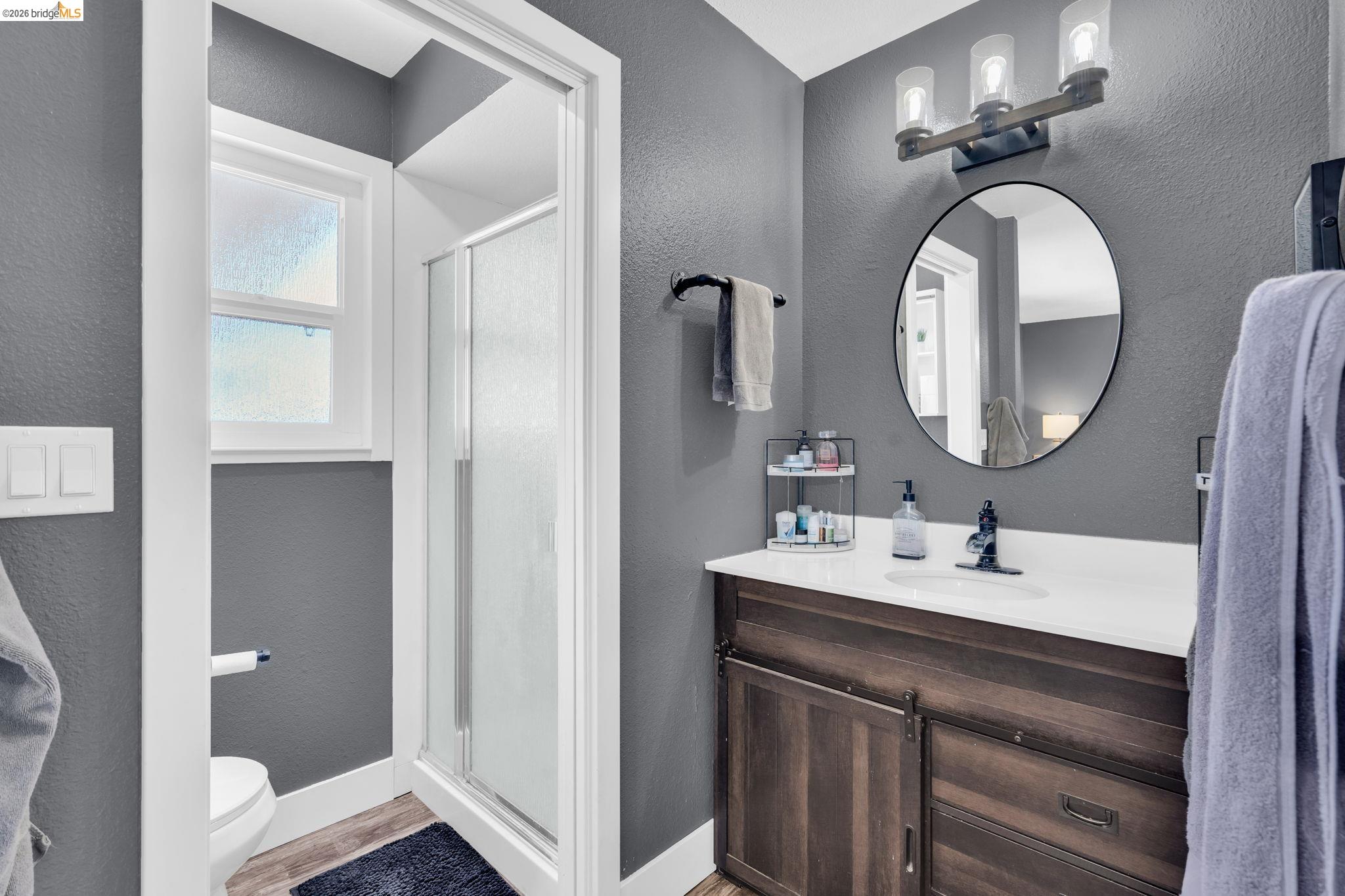 59 Old Stagecoach Road Brentwood, CA 94513 - Photo 28 of 70 Bathroom featuring a wood-finish vanity with a white countertop, an oval mirror, and a three-light vanity fixture
