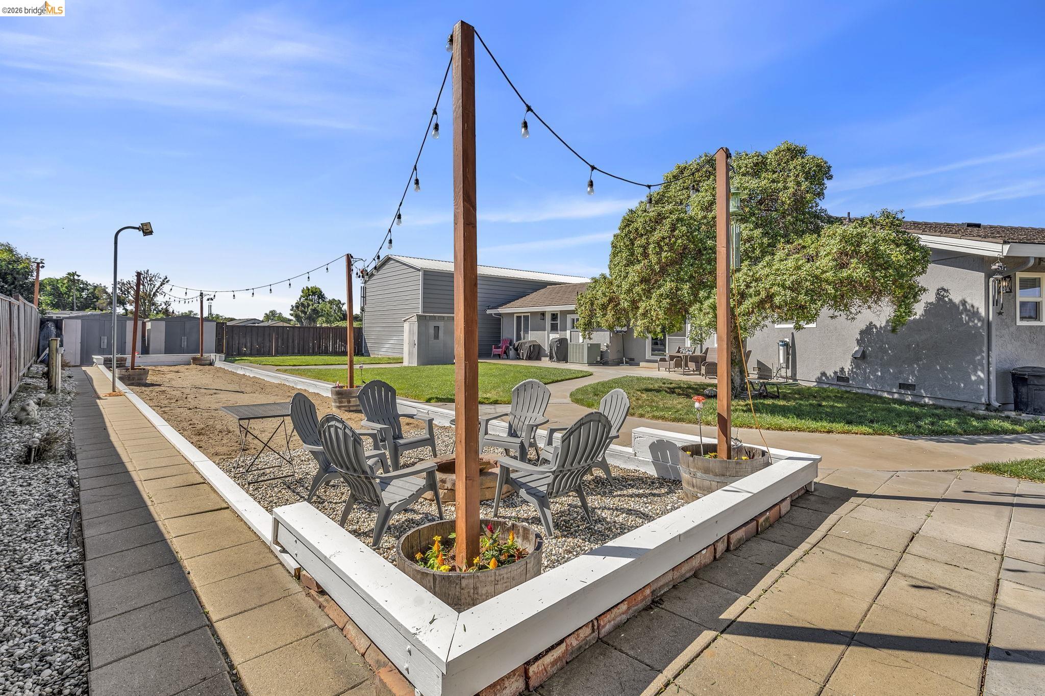 59 Old Stagecoach Road Brentwood, CA 94513 - Photo 56 of 70 Outdoor patio featuring a gravel surface, string lights, and a low white perimeter wall with brick detailing
