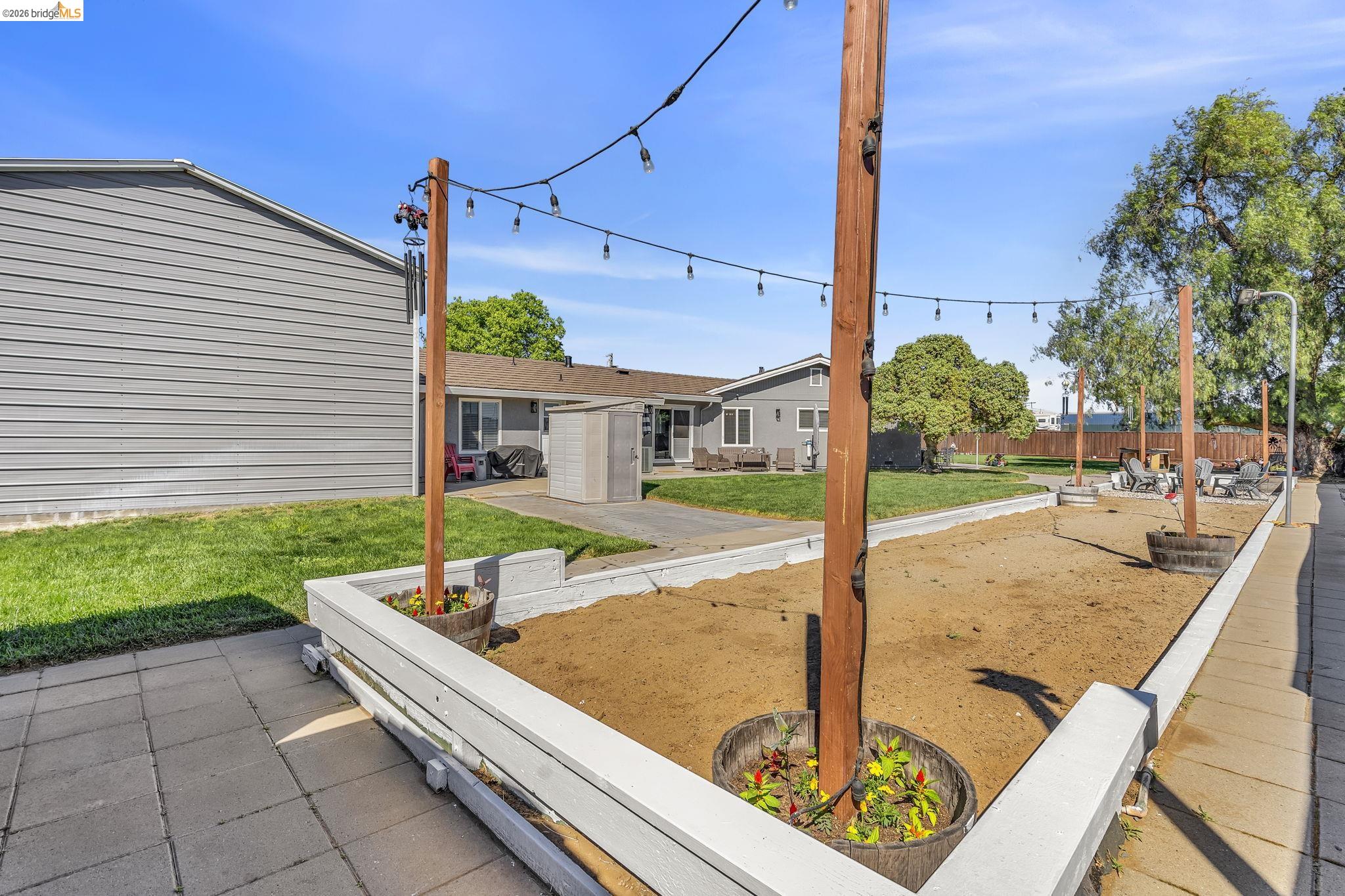 59 Old Stagecoach Road Brentwood, CA 94513 - Photo 57 of 70 Spacious outdoor area featuring a sand-filled court, string lighting, and low white perimeter walls
