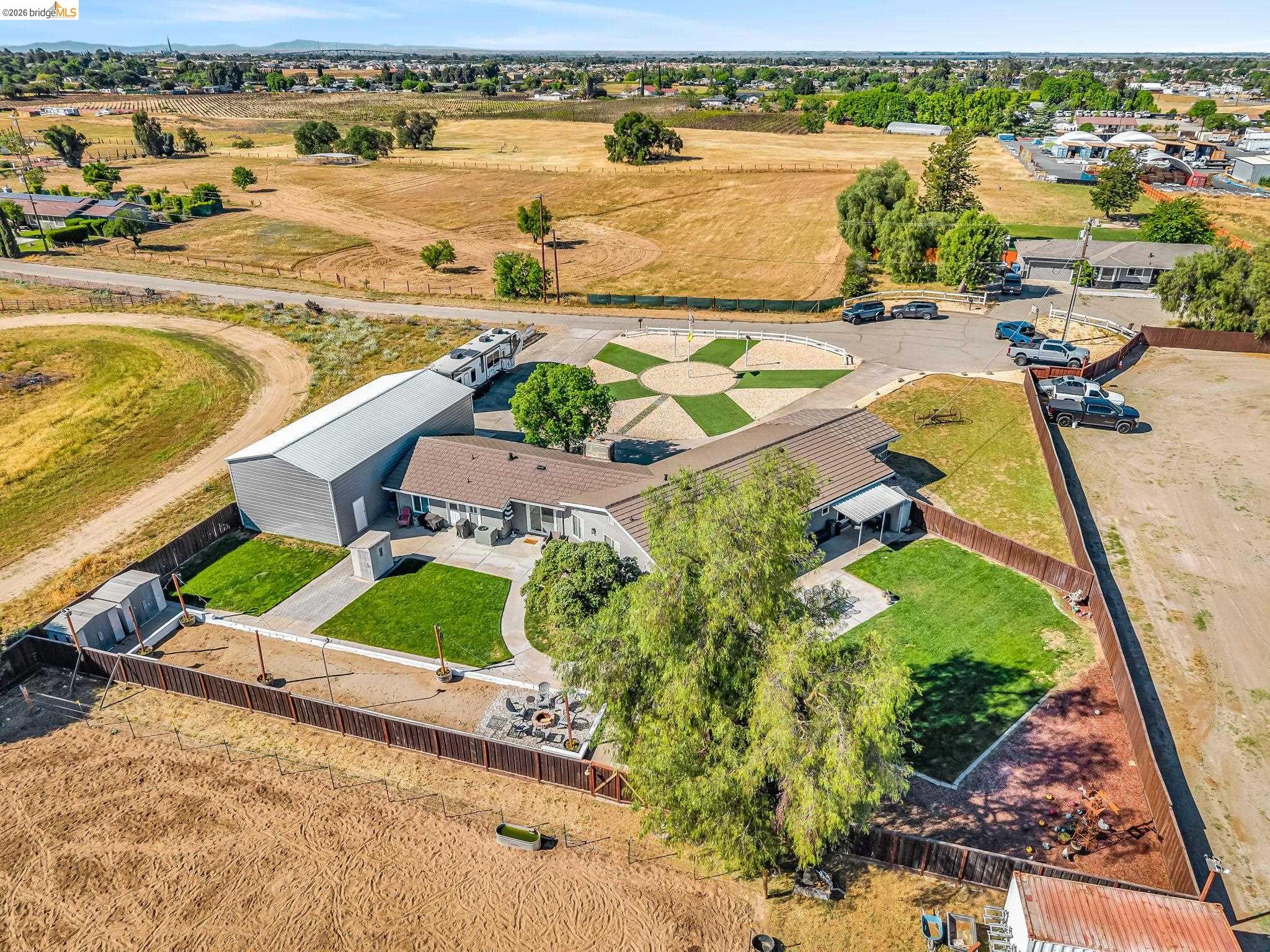 59 Old Stagecoach Road Brentwood, CA 94513 - Photo 65 of 70 Expansive property featuring a large metal outbuilding, manicured lawns, a circular paved driveway with a geometric turf inlay, a covered patio, and a dedicated fire pit area