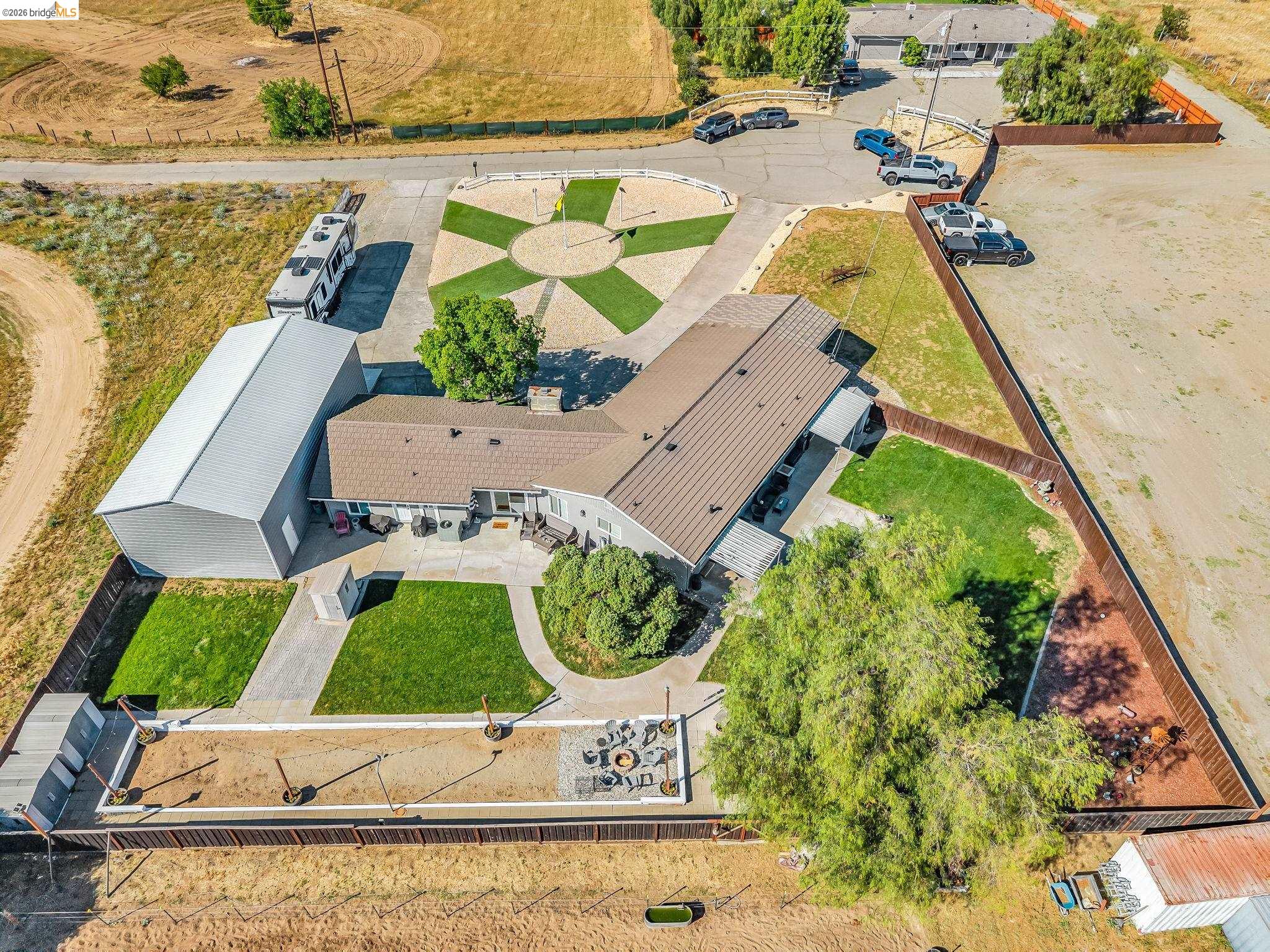 59 Old Stagecoach Road Brentwood, CA 94513 - Photo 68 of 70 Expansive property featuring a large metal barn, paved driveways, a circular artificial turf design, established trees, and a fenced perimeter