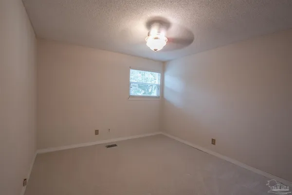 an empty room with windows and chandelier fan