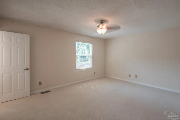 an empty room with closet and a ceiling fan