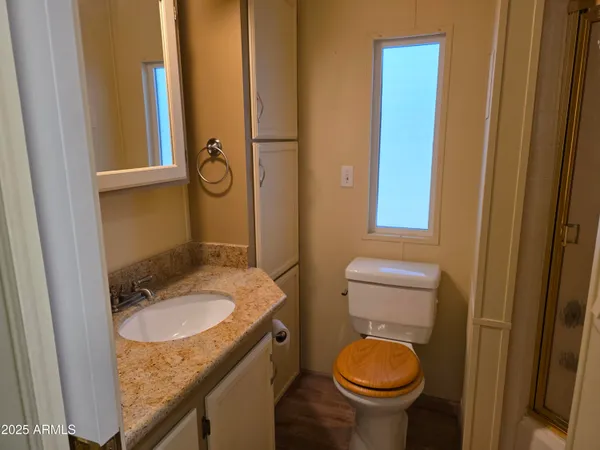 a bathroom with a granite countertop toilet sink and mirror