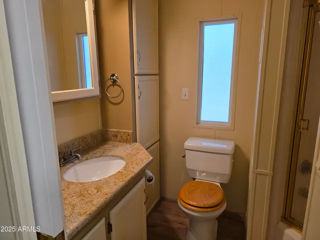 a bathroom with a granite countertop toilet sink and mirror