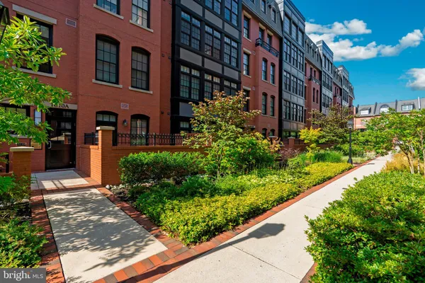 a front view of a multi story residential apartment building with yard and bench