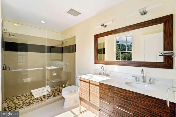 a bathroom with a double vanity sink toilet mirror and shower