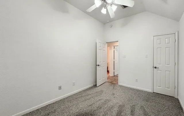 an empty room with a chandelier fan and wooden floor