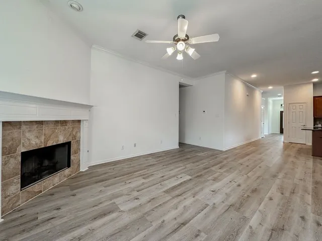 a view of an empty room with wooden floor and a fireplace