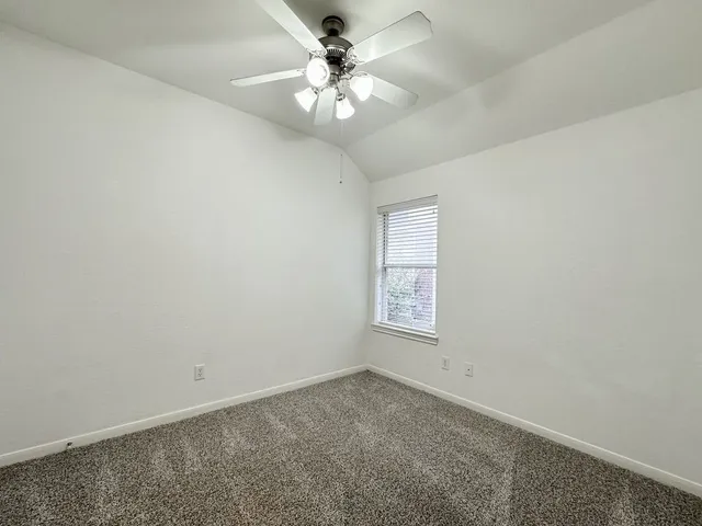 an empty room with windows and chandelier fan