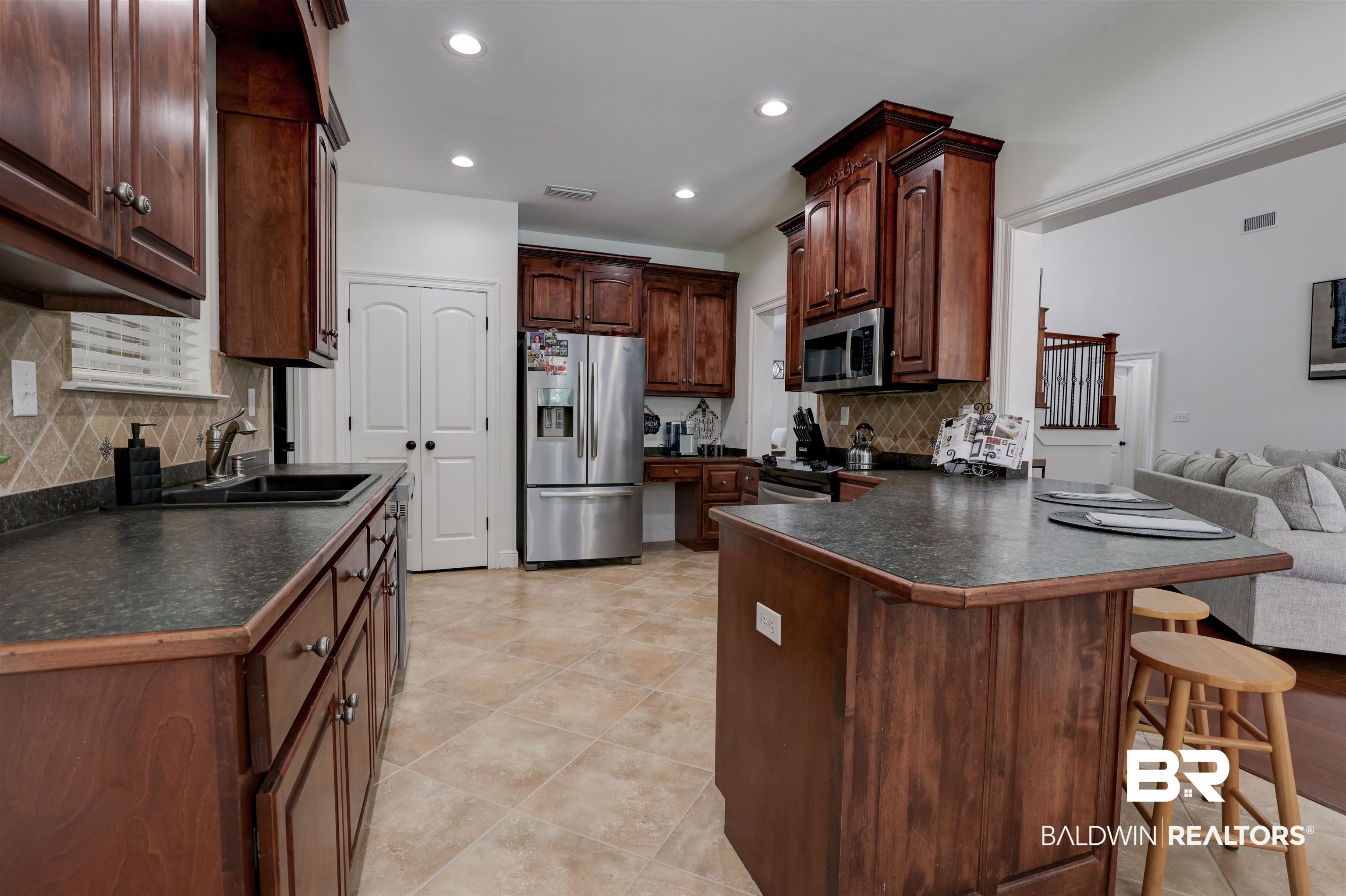 5565 Dawes Lane Theodore, AL 36582 - Photo 11 of 38 Kitchen with stainless steel appliances, sink, light tile patterned flooring, a kitchen bar, and tasteful backsplash