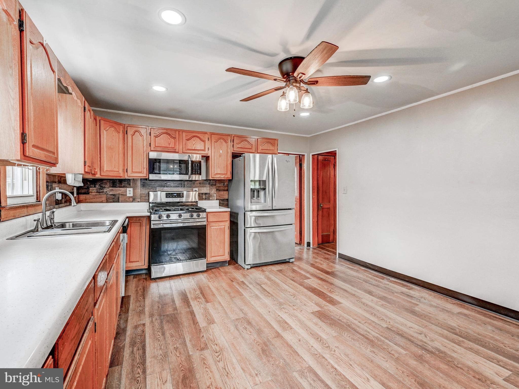 3206 Lynch Road Baltimore, MD 21219 - Photo 18 of 70 a kitchen with stainless steel appliances a stove top oven a sink dishwasher a refrigerator with white cabinets and wooden floor