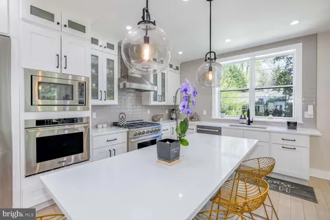 a kitchen with stainless steel appliances a refrigerator a stove a kitchen island with a dining table and chairs