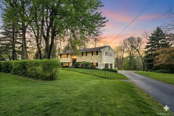 a front view of a house with a yard and trees