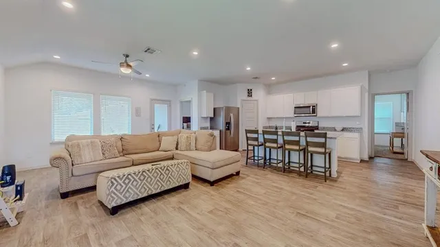 a living room with furniture and kitchen view with wooden floor