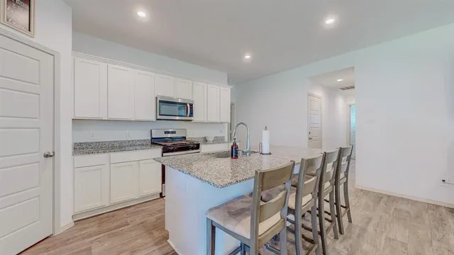 a kitchen with granite countertop white cabinets and stainless steel appliances