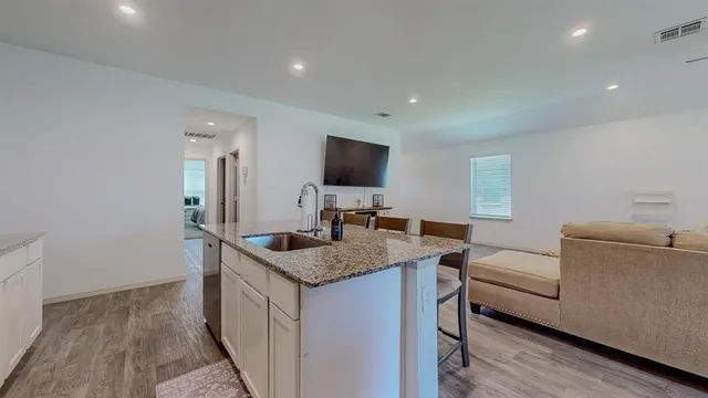 a view of kitchen island with stainless steel appliances granite countertop sink stove and a wooden floors