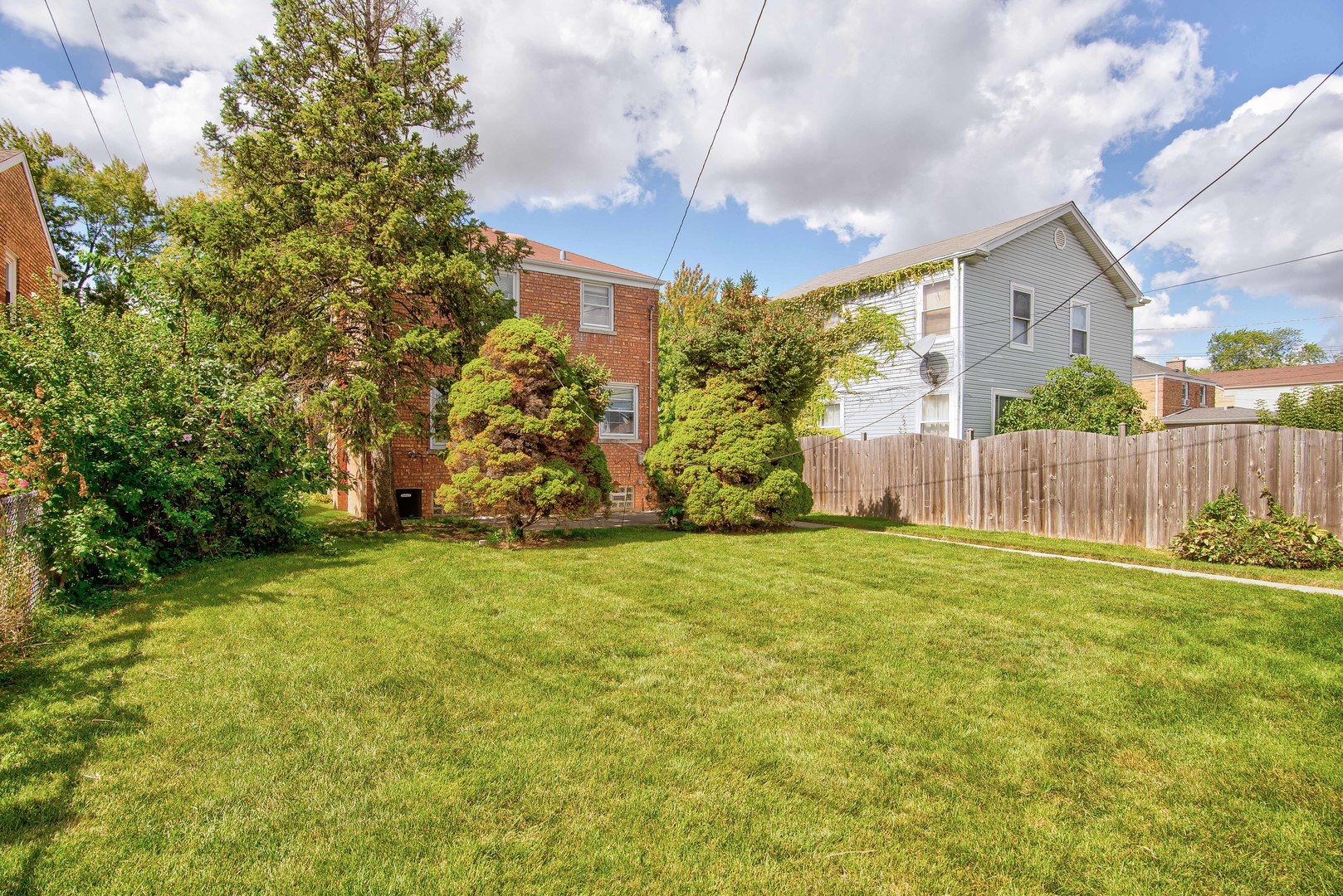 2441 Clarke Street River Grove, IL 60171 - Photo 20 of 25 a brick house with a yard plants and wooden fence