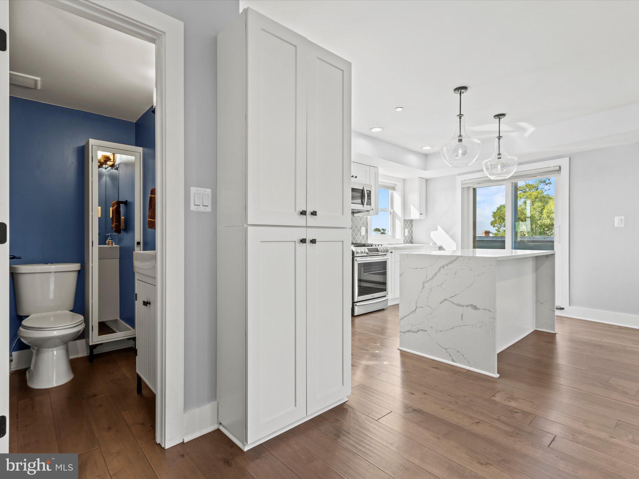 1267 Penn Street Northeast, Unit B Washington, DC 20002 - Photo 8 of 18 a large white kitchen with a refrigerator a sink dishwasher and white cabinets with wooden floor