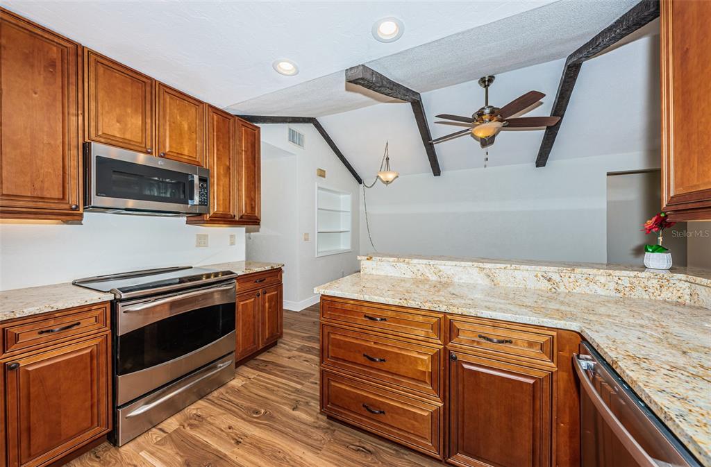 4723 114th Street North Madeira Beach, FL 33708 - Photo 13 of 41 a kitchen with kitchen island granite countertop a stove a sink and wooden cabinets