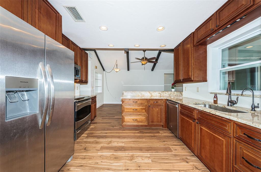 4723 114th Street North Madeira Beach, FL 33708 - Photo 15 of 41 a large kitchen with stainless steel appliances kitchen island granite countertop a refrigerator and a sink