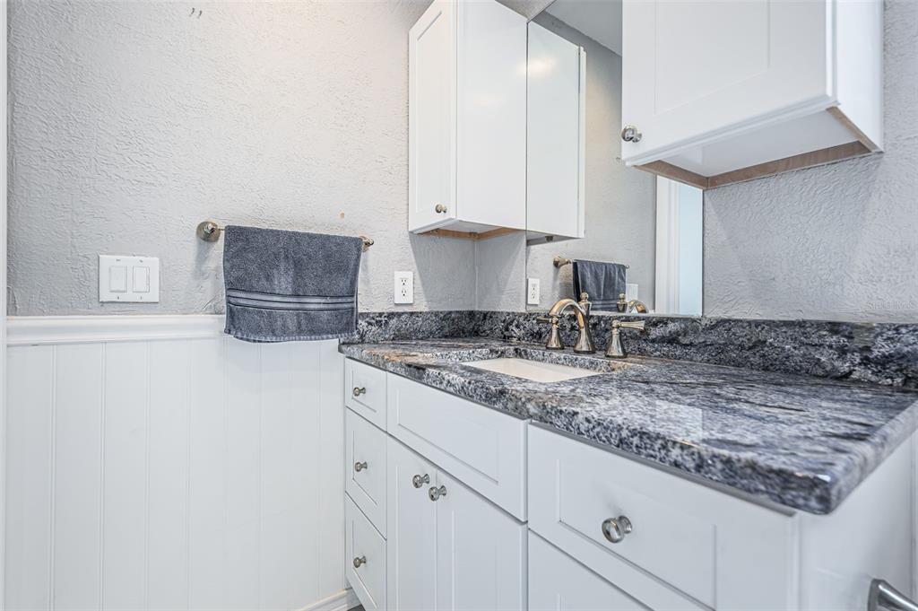 4723 114th Street North Madeira Beach, FL 33708 - Photo 27 of 41 a kitchen with granite countertop a sink a stove and white cabinets