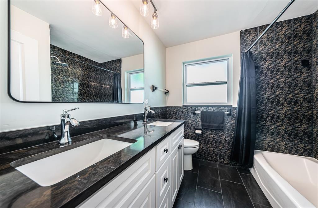 4723 114th Street North Madeira Beach, FL 33708 - Photo 30 of 41 a bathroom with a double vanity sink a mirror and a bathtub