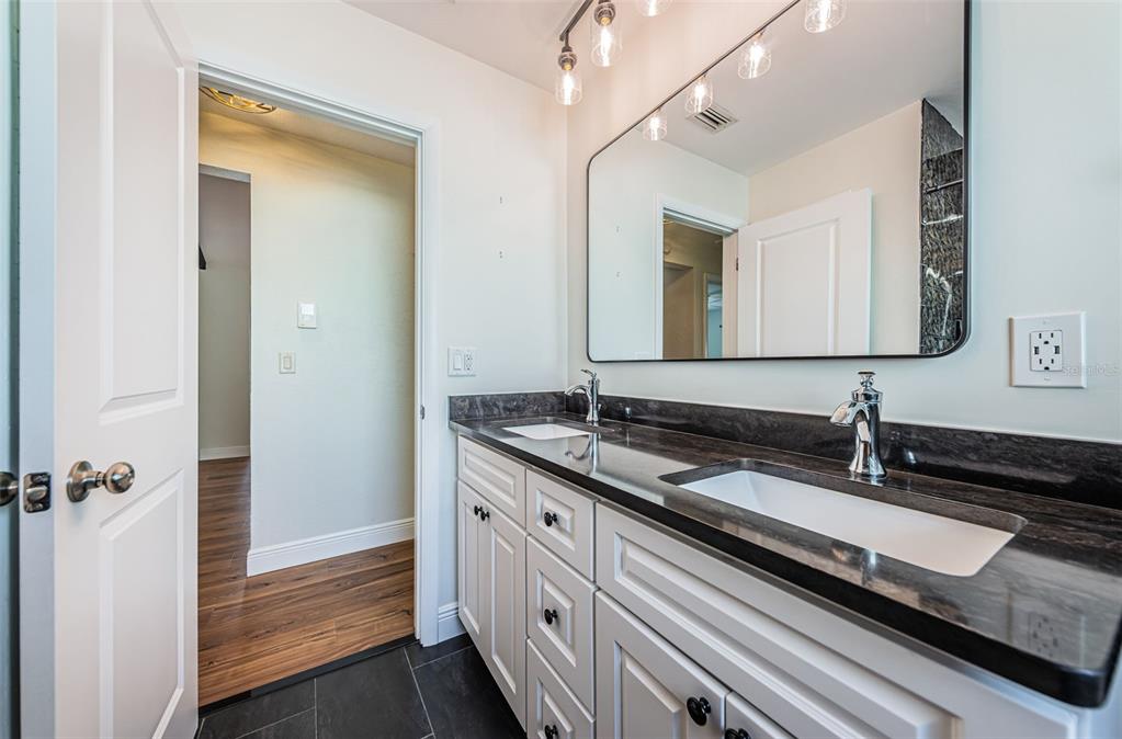 4723 114th Street North Madeira Beach, FL 33708 - Photo 32 of 41 a spacious bathroom with a granite countertop sink a mirror and a