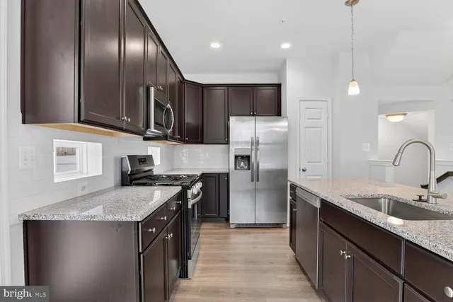 a kitchen with stainless steel appliances granite countertop a sink a stove and refrigerator