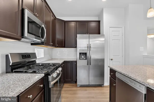 a kitchen with stainless steel appliances granite countertop a stove refrigerator and microwave